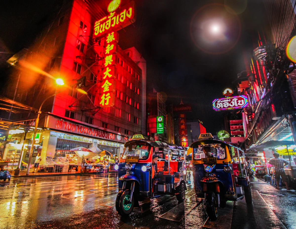夜のバンコクのネオンとトゥクトゥク。旅行中にタトゥーを入れる人が多い街の風景