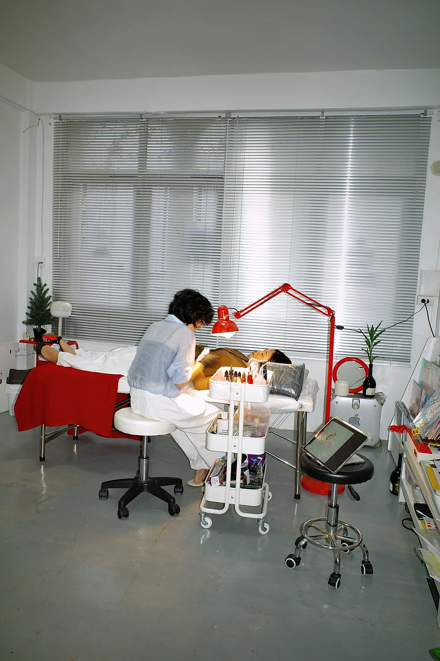 Wide view of Naive Flora Tattoo studio in Chatuchak, Bangkok, with the artist tattooing under the red lamp