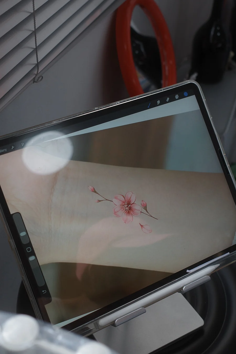 iPadのProcreateで、お客さまの腕の写真に桜のデザインを配置して確認している様子