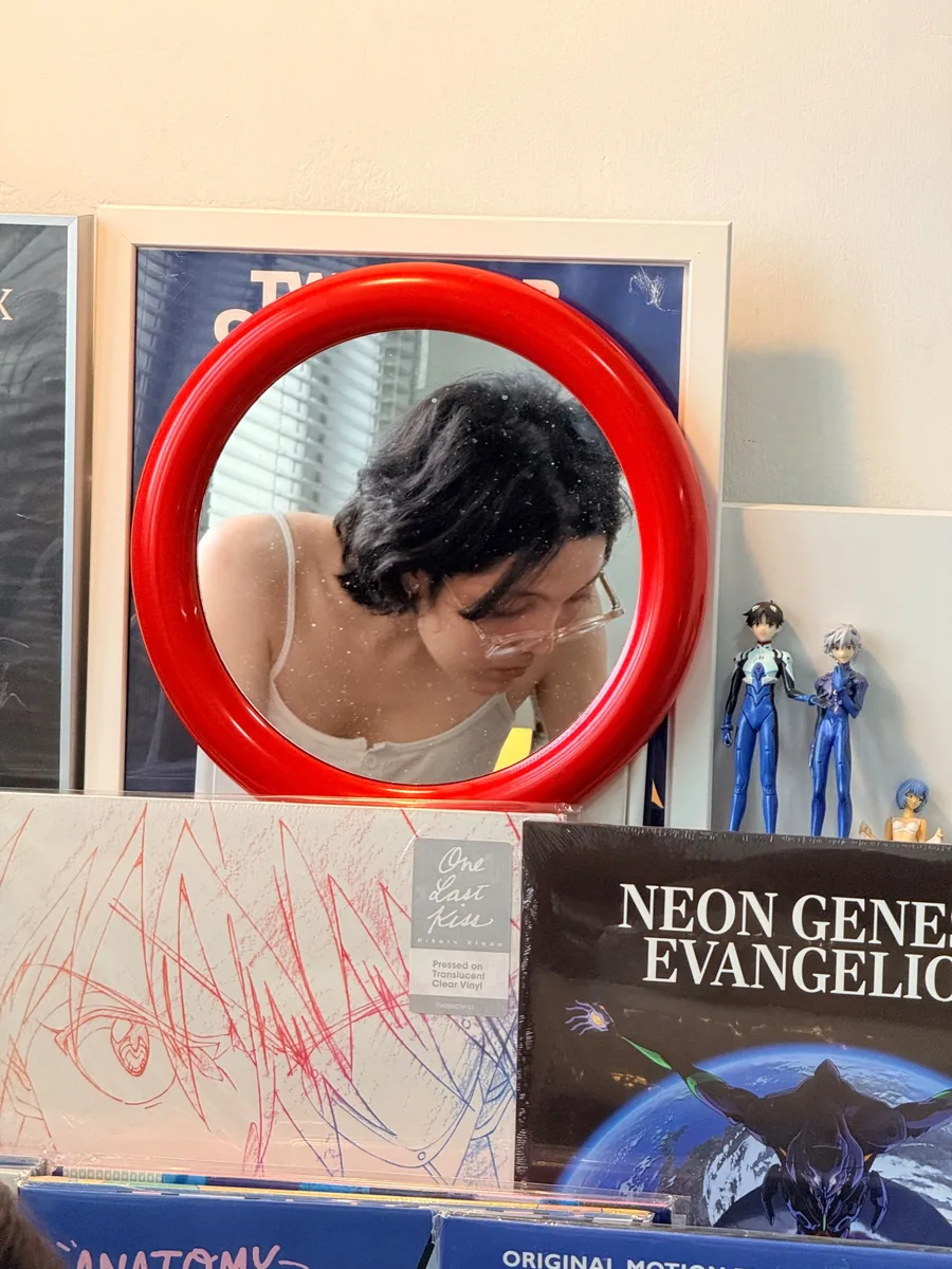 A corner of the studio with a round red mirror and a rack of records