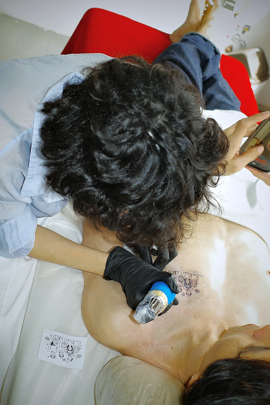 Close-up of the artist tattooing the family portrait on the client's upper chest