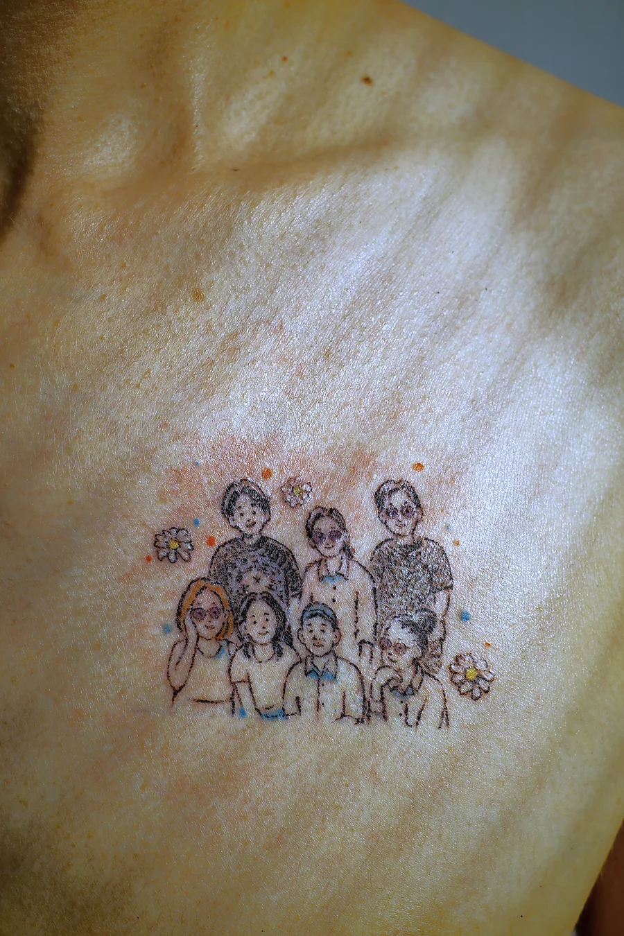 The finished family portrait tattoo in soft window light, with shadows from the blinds across the chest
