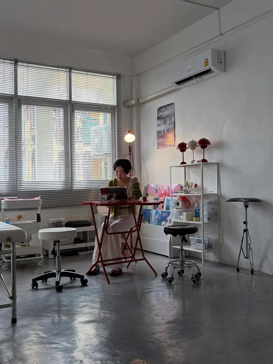 The artist drawing designs at the red table in the studio, birthplace of every flash design