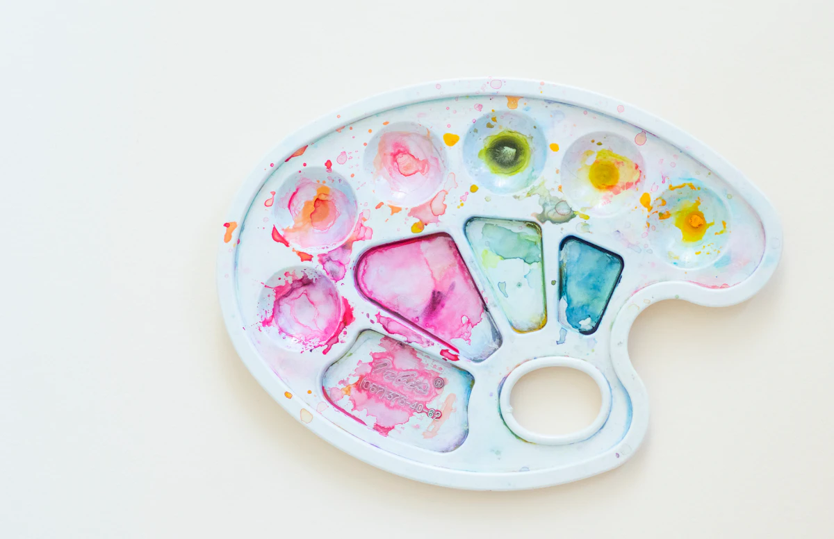 ピンクや黄色、ターコイズの水彩絵の具がのったパレット。肌のトーンに合わせたタトゥーの色選びのイメージ